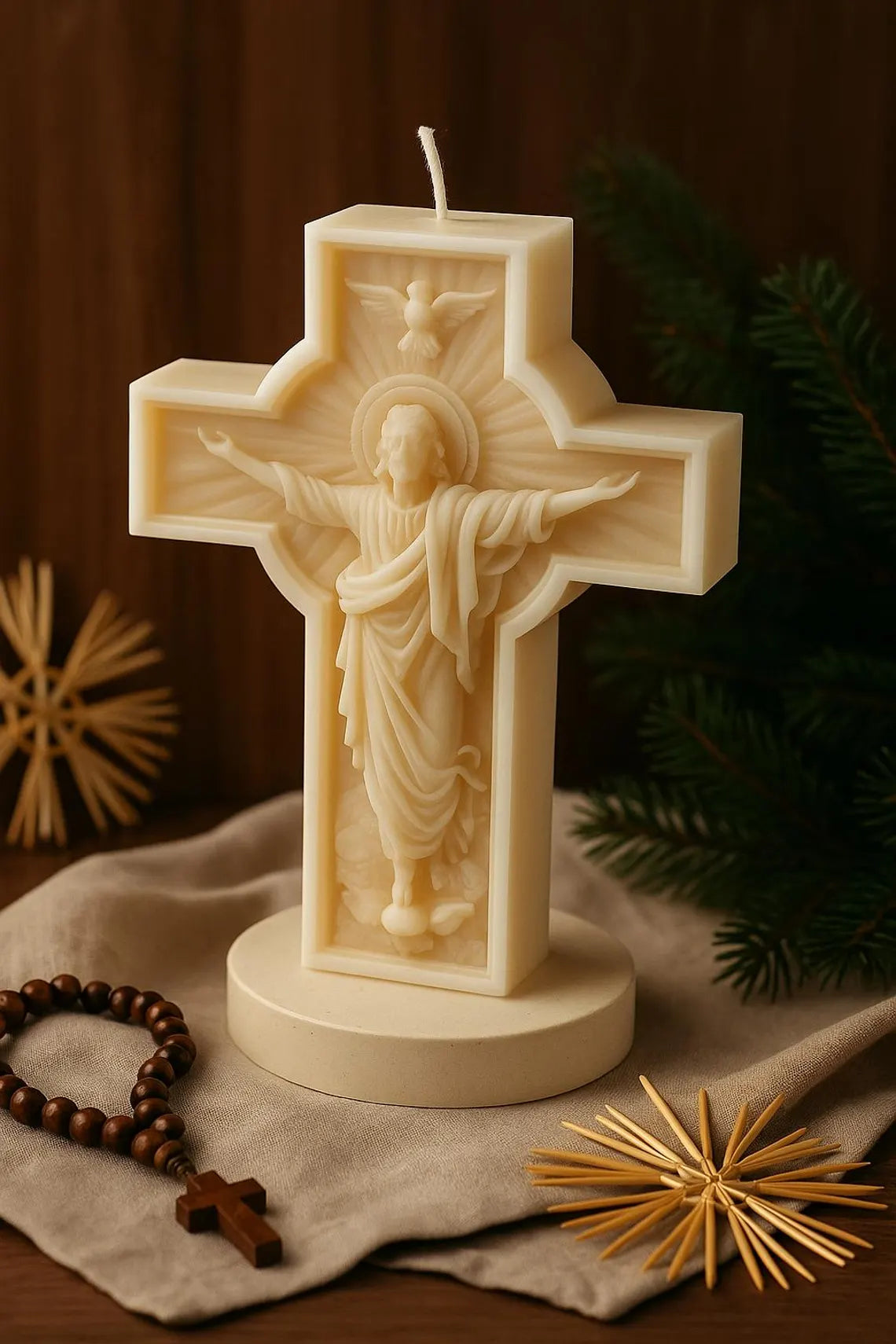 Weiße Kerze in Kreuzform mit detailreicher Jesus-Figur und ausgebreiteten Armen, unangezündet, auf rundem Sockel arrangiert mit Rosenkranz und weihnachtlicher Dekoration im warmen Licht.